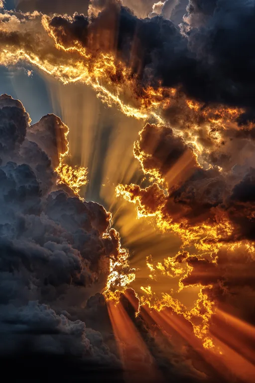 Dramatic sunbeams pierce through dark, stormy clouds, illuminating